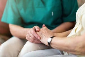 Woman in hospice care holds hands with a nurse