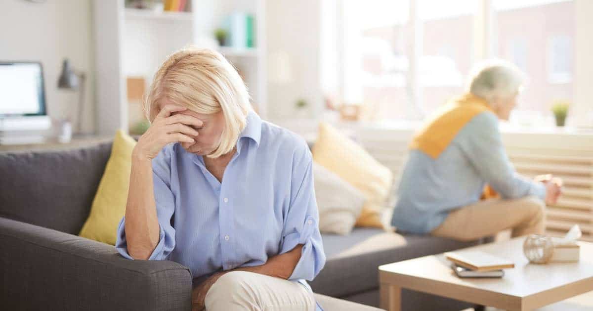 Senior couple fighting in a home, close up on the women with her head in her hands