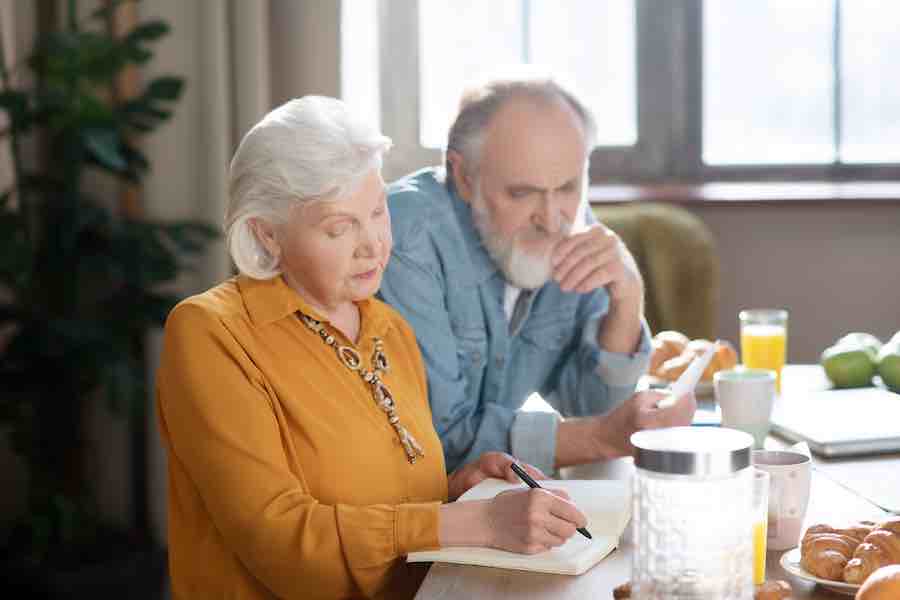 Elderly married couple sitting at the table making calculations