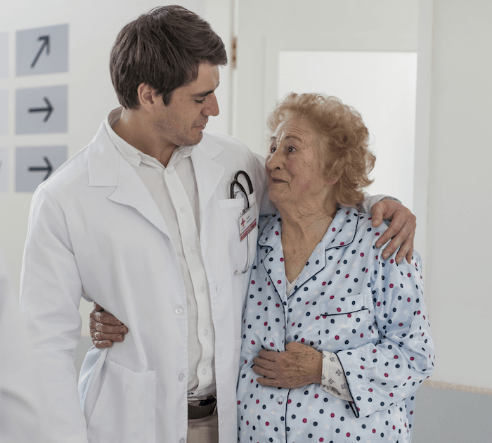 Doctor embracing elderly patient on hospital floor