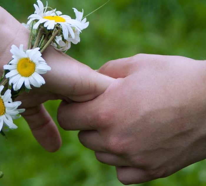 Hands touching in Hasupport with flowers.