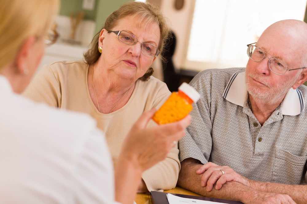 Doctor or nurse explaining hospice medications to a senior couple.