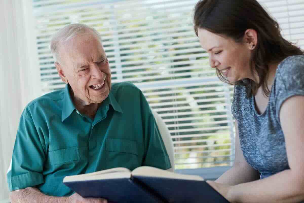 Elderly man in a green shirt with a female hospice volunteer.