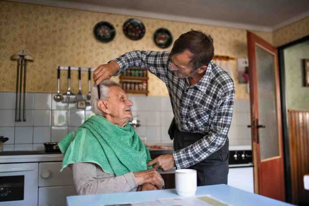 Old man getting hair brushed by his family in home hospice caregiver.