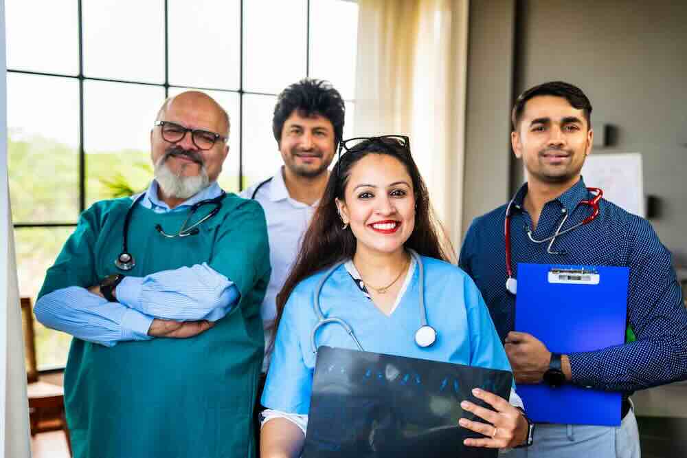 Caring hospice team in blue scrubs standing by a window.