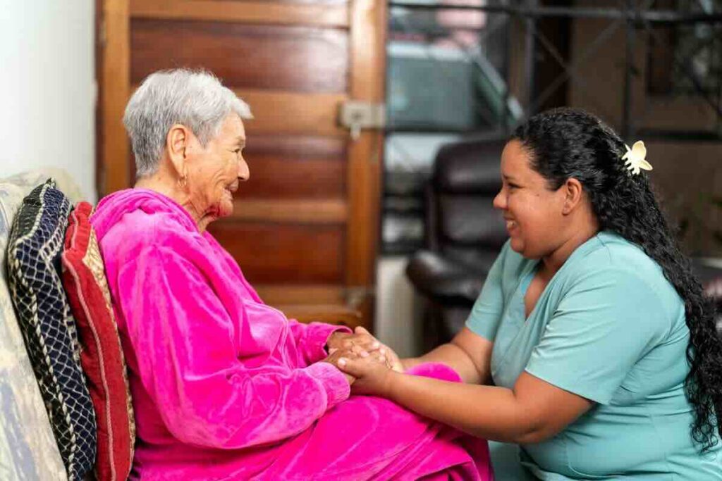 Elder woman in pink with a caring hospice nurse.
