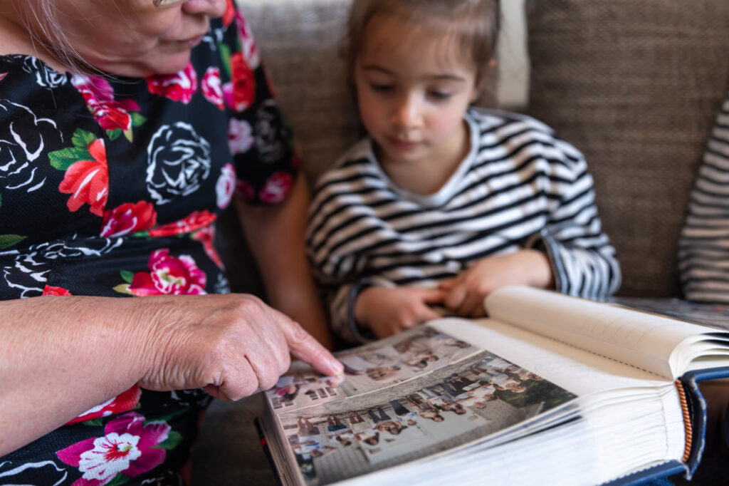 Older woman looking at a photo album with a young girl after talking with a hospice social worker.